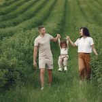 A happy family walking in a lush, green rural field together.
