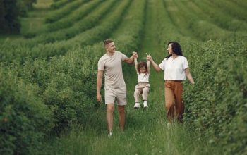 A happy family walking in a lush, green rural field together.