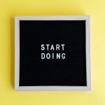 Black message board with 'Start Doing' on a bright yellow background for inspiration.