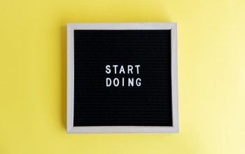 Black message board with 'Start Doing' on a bright yellow background for inspiration.