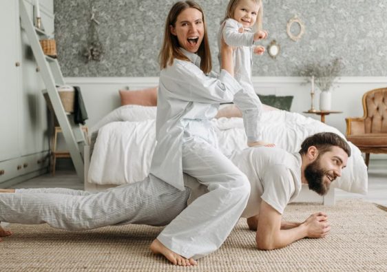 A cheerful family enjoys bonding and playing together on a cozy morning in a stylish bedroom.